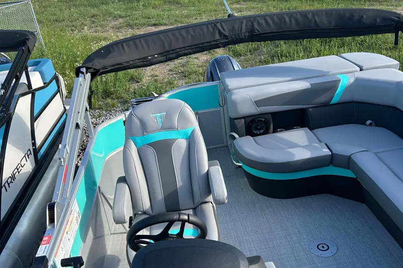 Slide: The Image of 2025 Trifecta 20CCS boat interior with gray and teal seating, steering wheel, and open canopy. - 7