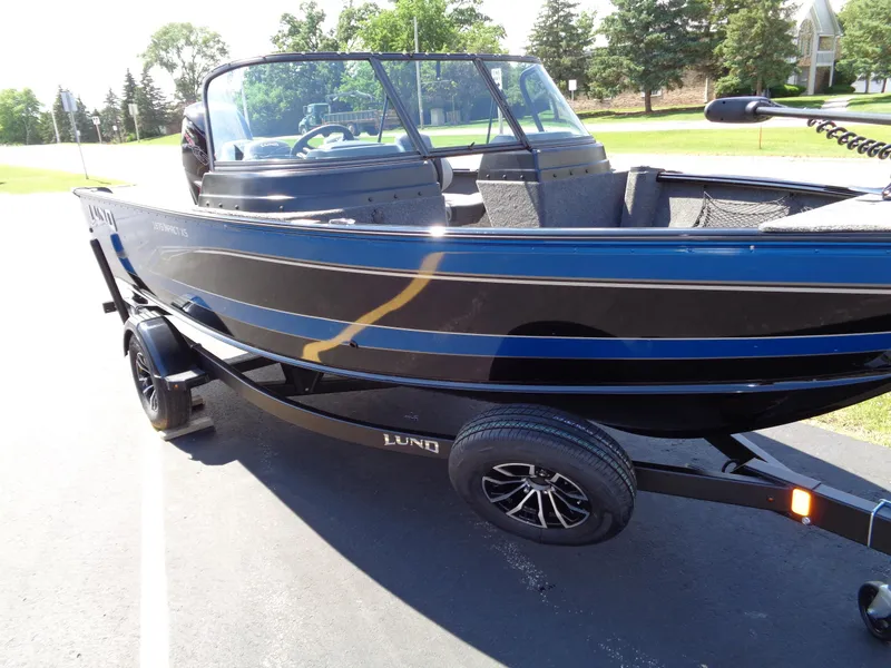 Slide: The Image of 2024 Lund 1875 Impact XS boat on trailer, black exterior, parked outdoors. - 17