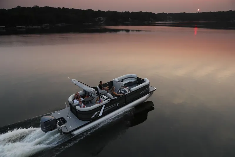Slide: The Image of 2025 Starcraft EXS 3 Q pontoon boat cruising on a serene lake at sunset. - 9