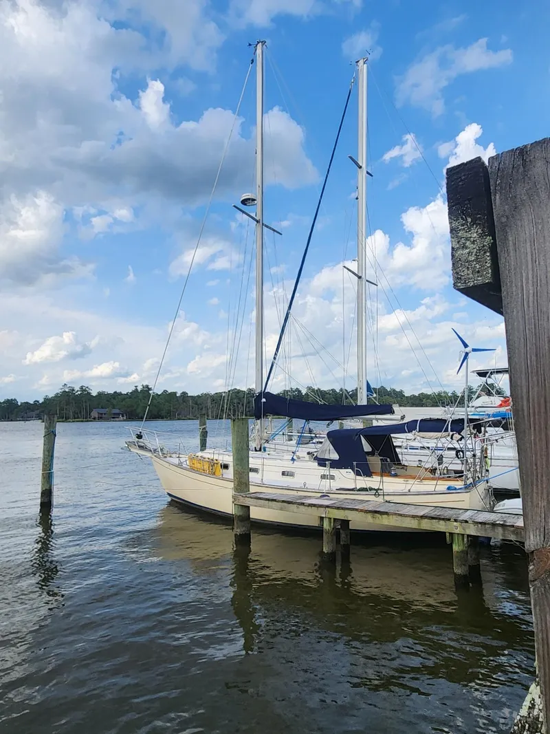 Slide: The Image of 1989 Island Packet 35 sailboat docked on a sunny day with cloudy skies. - 2