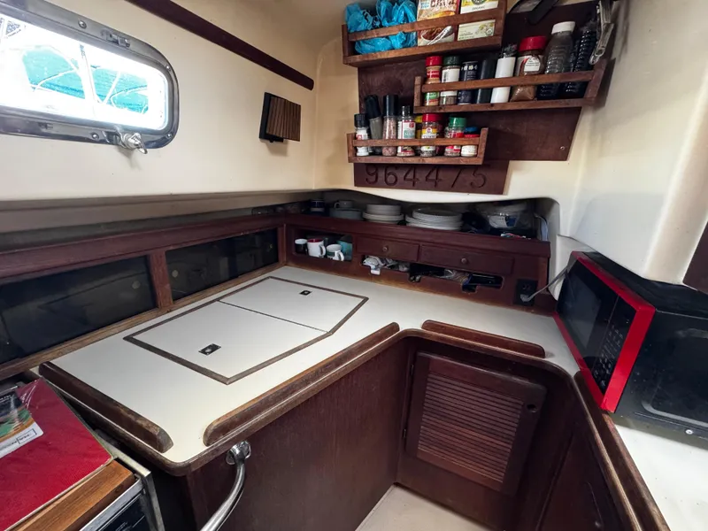 Slide: The Image of Interior of 1989 Island Packet 35 sailboat with cozy seating and compact kitchen area. - 53
