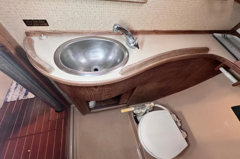 Slide: The Image of 1989 Island Packet 35 yacht bathroom with sink and toilet, featuring wooden cabinetry. - 78