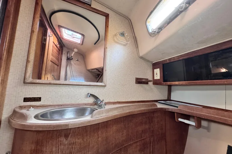 Slide: The Image of 1989 Island Packet 35 yacht bathroom with sink, mirror, and wooden cabinetry. - 79