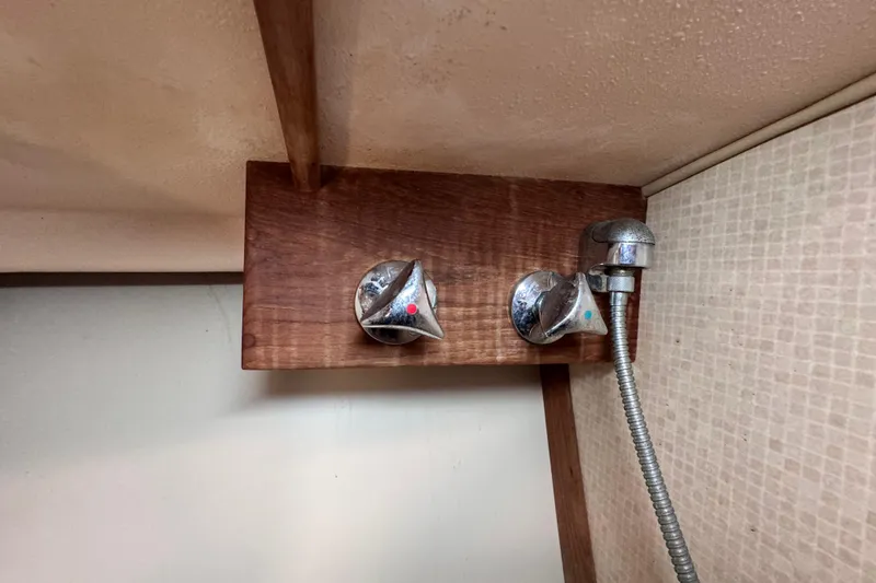 Slide: The Image of 1989 Island Packet 35 boat shower with chrome fixtures and wooden paneling. - 81