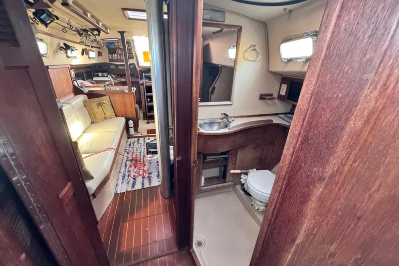 Slide: The Image of Interior of 1989 Island Packet 35 sailboat showing cabin and bathroom with wooden finishes. - 83