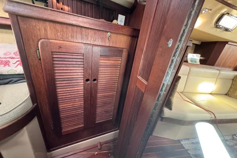 Slide: The Image of Interior of 1989 Island Packet 35 sailboat with wooden cabinetry and seating area. - 89