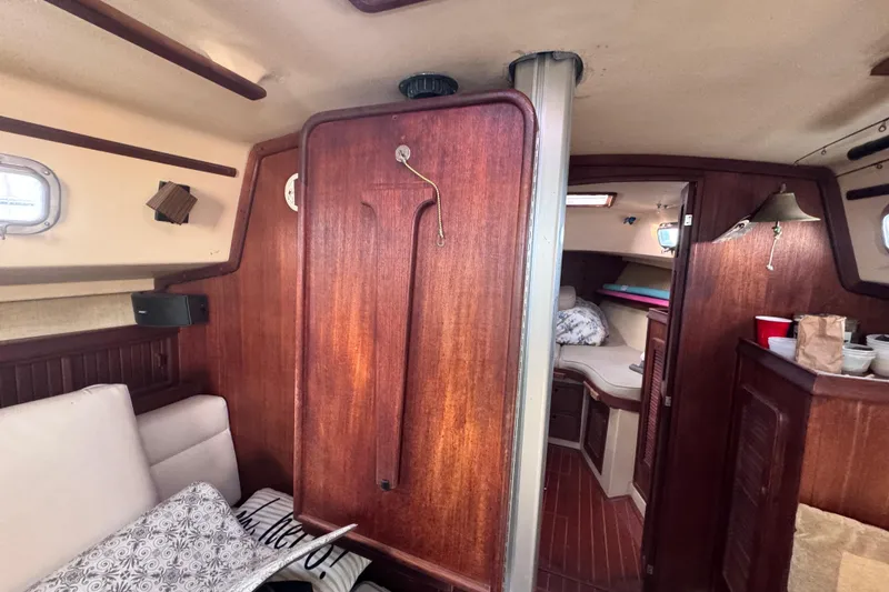Slide: The Image of Interior of 1989 Island Packet 35 sailboat with wooden finishes and cozy seating area. - 95