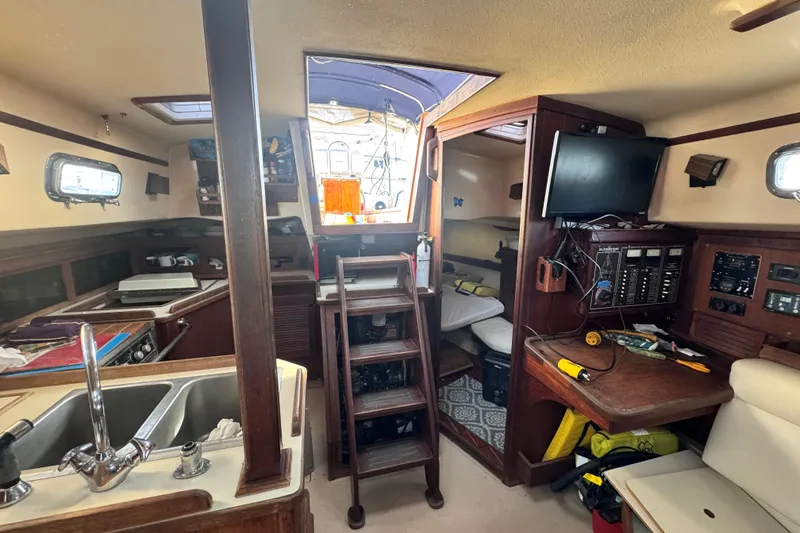 Slide: The Image of Interior of 1989 Island Packet 35 sailboat with kitchen, seating, and navigation equipment. - 96