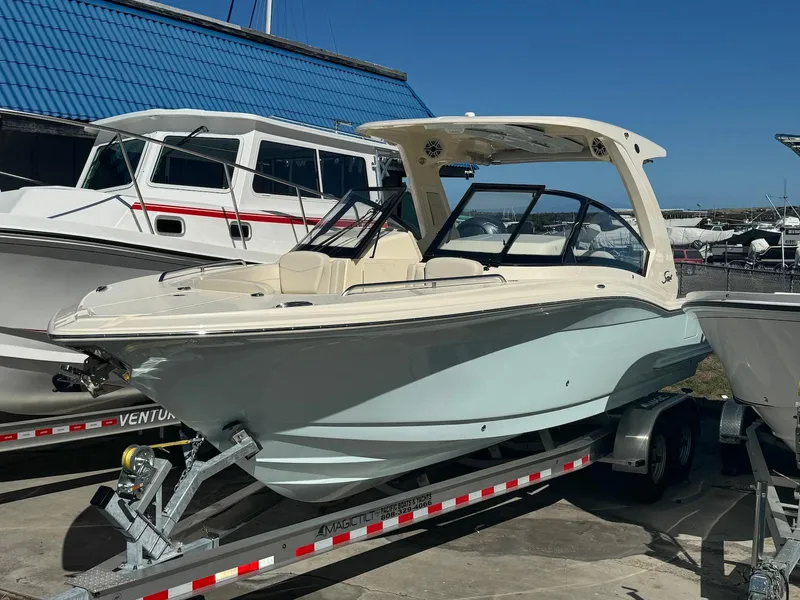 Slide: The Image of 2025 Scout 277 Dorado boat on trailer, parked at marina under clear blue sky. - 10