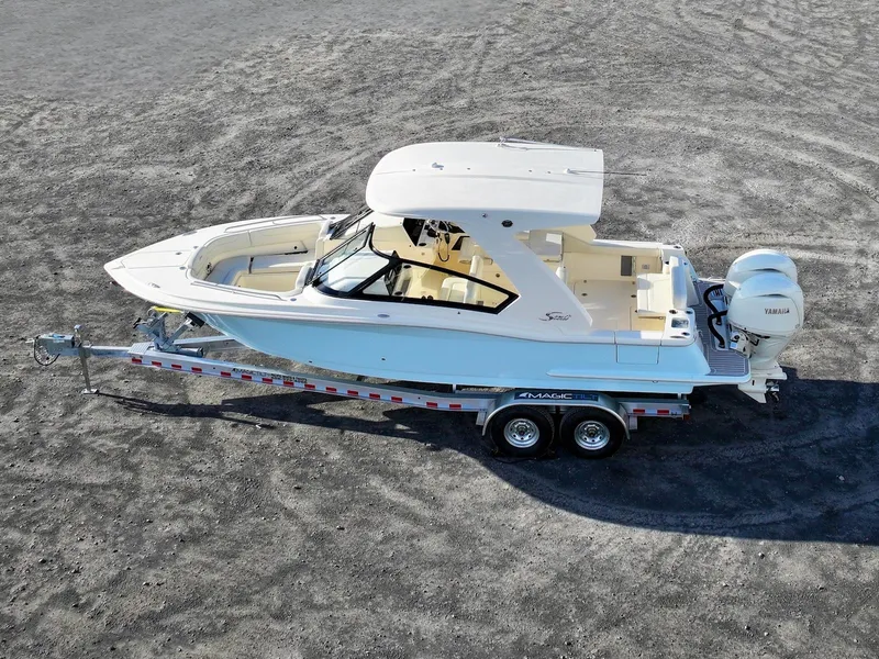 Slide: The Image of 2025 Scout 277 Dorado boat on trailer, parked on gravel surface. - 2