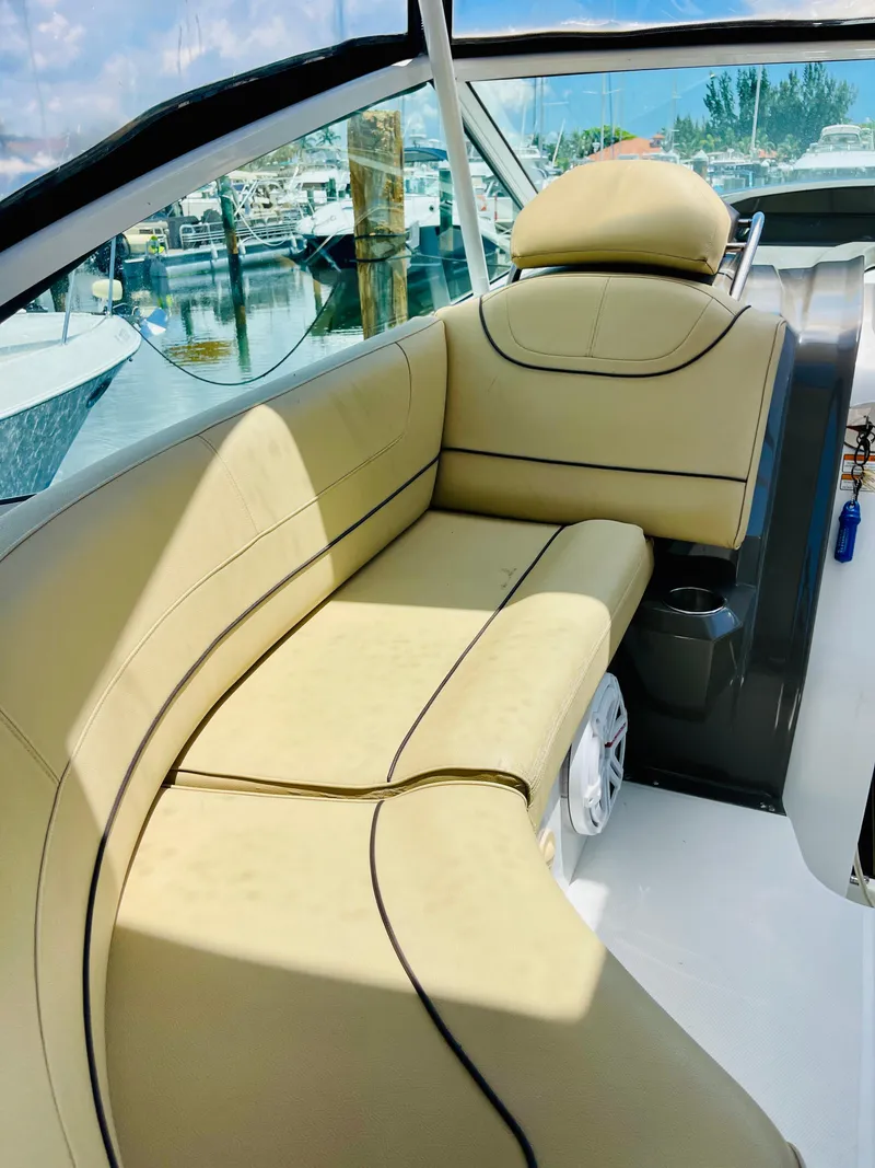 Slide: The Image of 2012 Cruisers 350 Express boat interior with beige seating at a marina. - 18