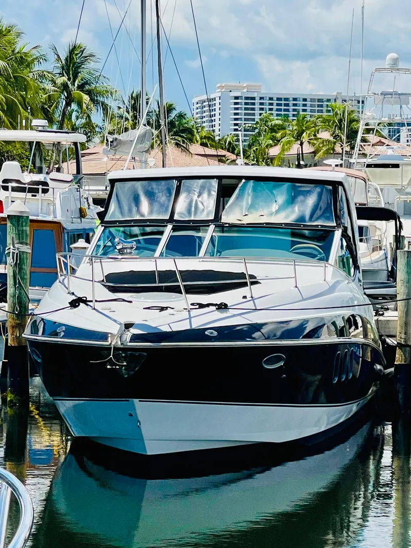 Slide: The Image of 2012 Cruisers 350 Express yacht docked in a marina with palm trees and buildings in the background. - 2