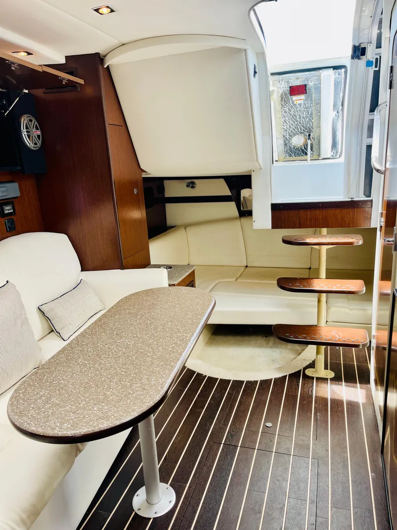 Slide: The Image of 2012 Cruisers 350 Express cabin interior with modern seating, table, and wooden steps. - 36