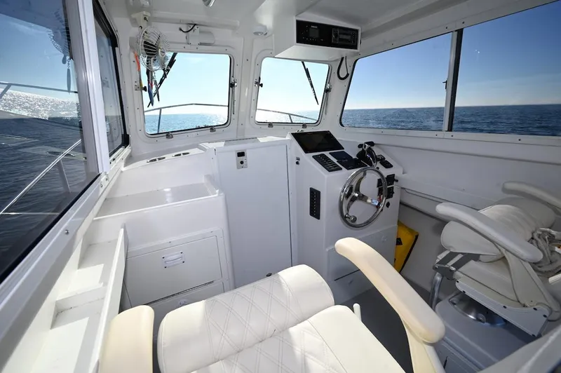 Slide: The Image of 2025 Steiger Craft 255 Miami boat interior with steering wheel, ocean view, and modern controls. - 7