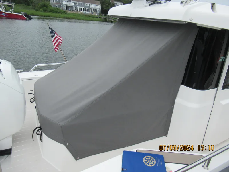 Slide: The Image of Axopar Mark II 2018 boat with gray cover, docked by a river with American flag. - 29