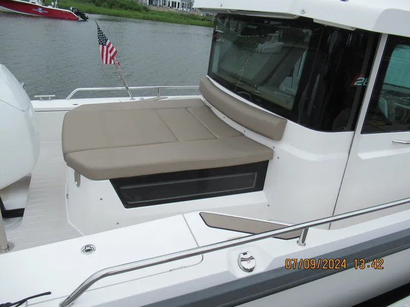 Slide: The Image of 2018 Axopar Mark II boat with beige seating, docked by a river with an American flag. - 37