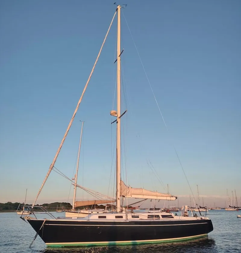Slide: The Image of 1983 Islander 40 sailboat anchored in calm waters at sunset. - 0