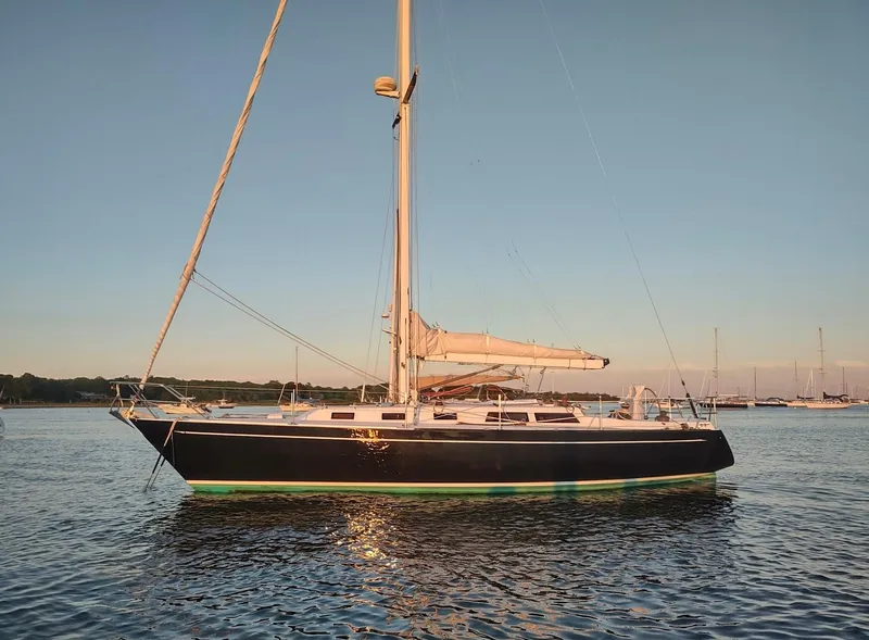 Slide: The Image of 1983 Islander 40 sailboat anchored on calm water at sunset. - 1