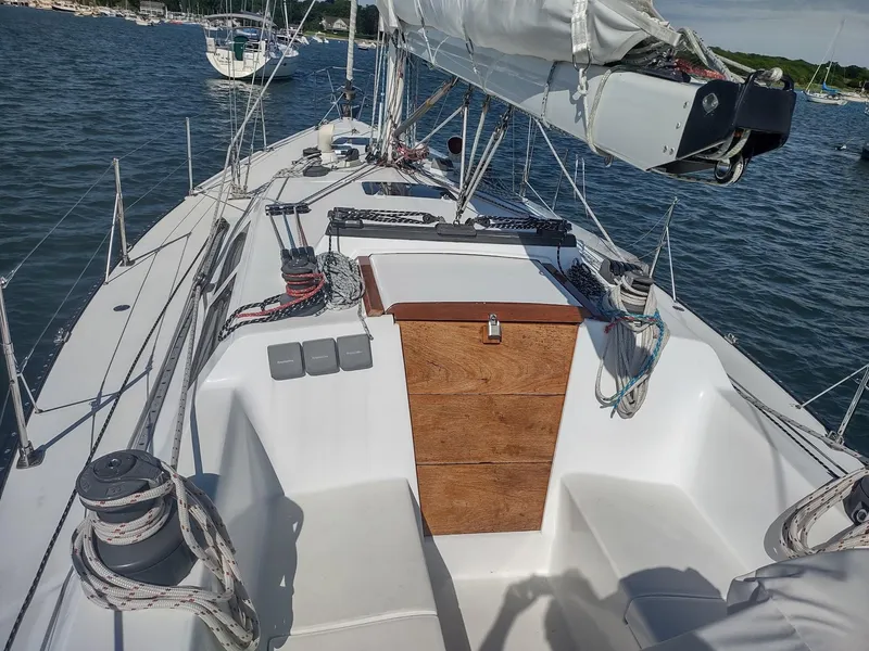 Slide: The Image of 1983 Islander 40 sailboat deck with rigging and wooden hatch, anchored in a marina. - 11