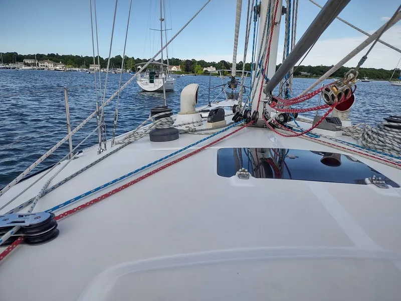 Slide: The Image of 1983 Islander 40 sailboat deck with rigging and ropes on a calm water body. - 13