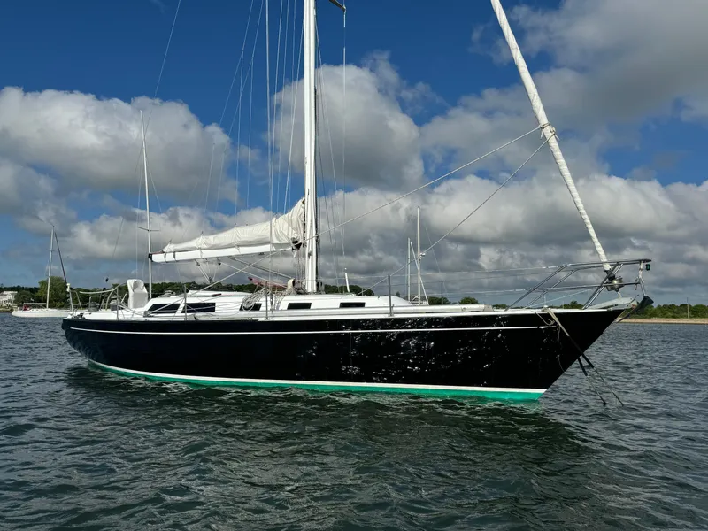 Slide: The Image of 1983 Islander 40 sailboat on calm water with blue sky and clouds. - 2
