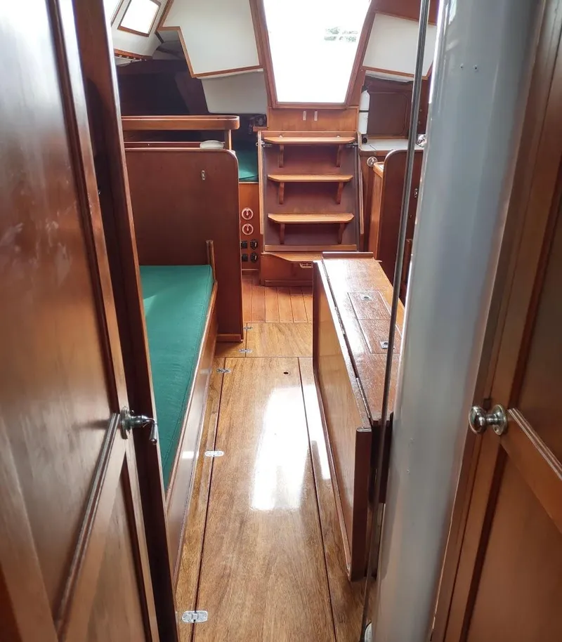 Slide: The Image of Interior of 1983 Islander 40 sailboat with wooden furnishings and green cushions. - 23