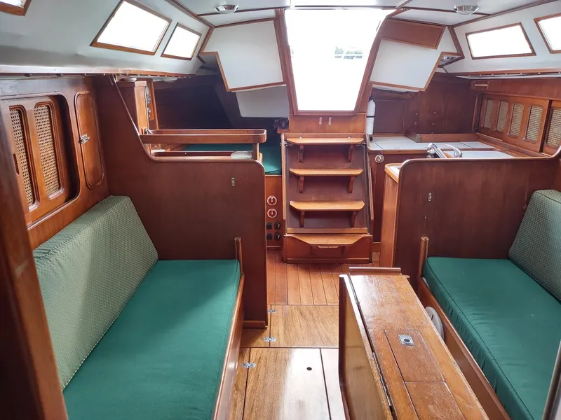 Slide: The Image of Interior of 1983 Islander 40 sailboat with wooden furnishings and green cushions. - 24