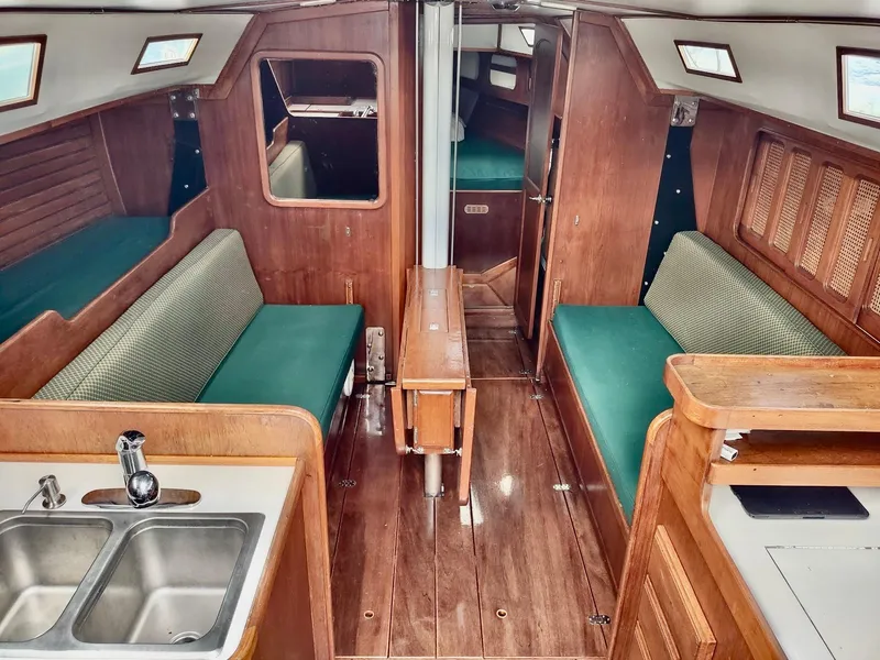 Slide: The Image of 1983 Islander 40 sailboat interior with wood finish and green upholstery. - 25