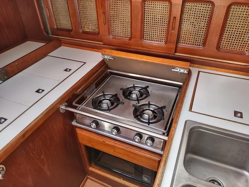 Slide: The Image of 1983 Islander 40 yacht kitchen with stove, sink, and wooden cabinetry. - 26