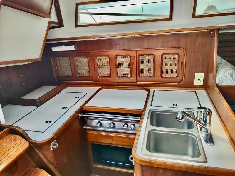 Slide: The Image of 1983 Islander 40 sailboat kitchen with stove, sink, and wooden cabinetry. - 27