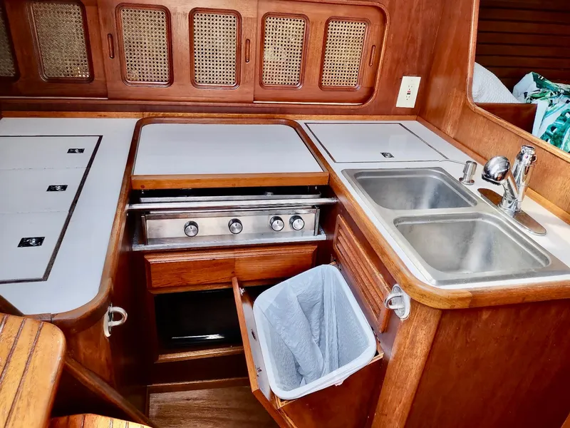 Slide: The Image of 1983 Islander 40 yacht kitchen with stove, double sink, and wooden cabinetry. - 28