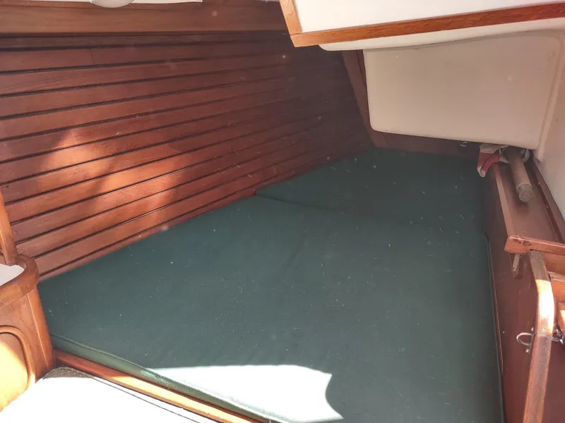 Slide: The Image of Interior cabin of 1983 Islander 40 sailboat with wooden paneling and green mattress. - 35