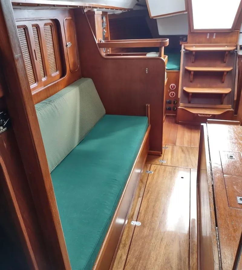 Slide: The Image of 1983 Islander 40 sailboat interior with green cushions and wooden cabinetry. - 38