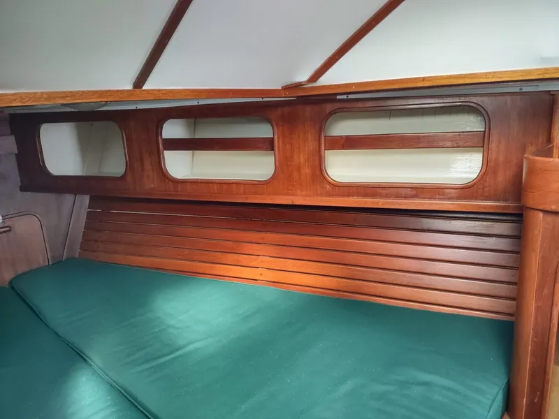 Slide: The Image of Interior cabin of 1983 Islander 40 sailboat with wooden paneling and green cushions. - 39
