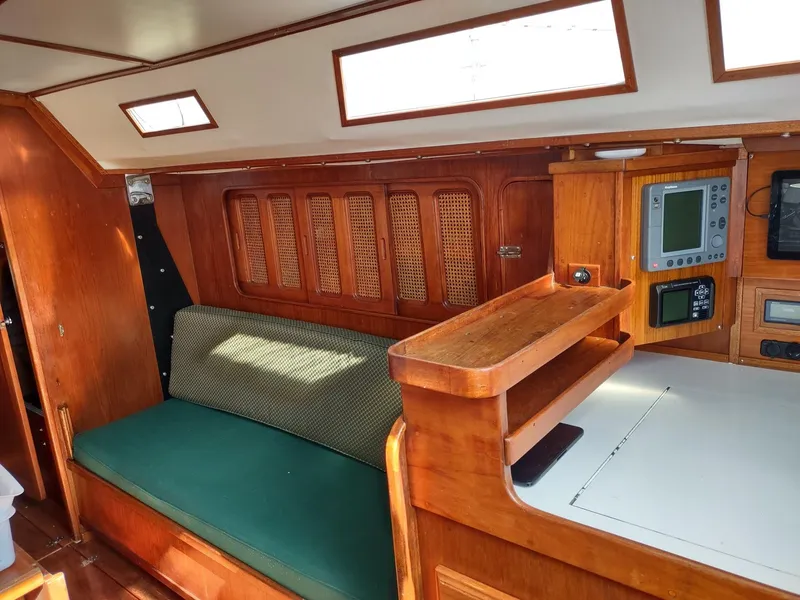 Slide: The Image of Interior of 1983 Islander 40 sailboat with wooden cabinetry and green cushioned seating. - 41