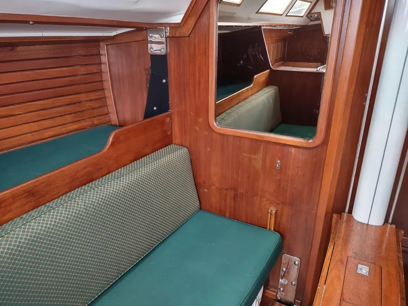 Slide: The Image of Interior of 1983 Islander 40 sailboat with green cushioned seating and wooden paneling. - 43