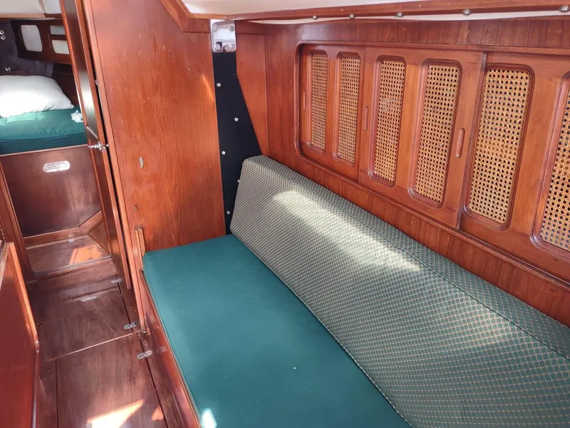 Slide: The Image of Interior of 1983 Islander 40 sailboat with green cushioned seating and wooden cabinetry. - 45