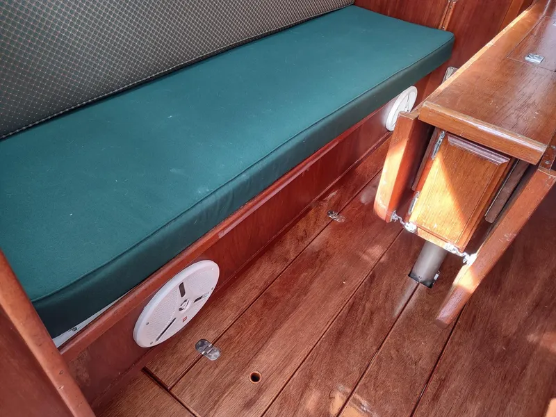 Slide: The Image of Interior of 1983 Islander 40 sailboat with green cushioned seating and wooden flooring. - 46
