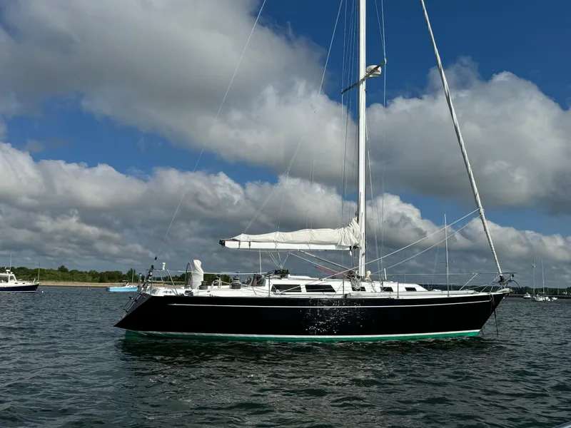 Slide: The Image of 1983 Islander 40 sailboat on calm water under a blue sky with clouds. - 5
