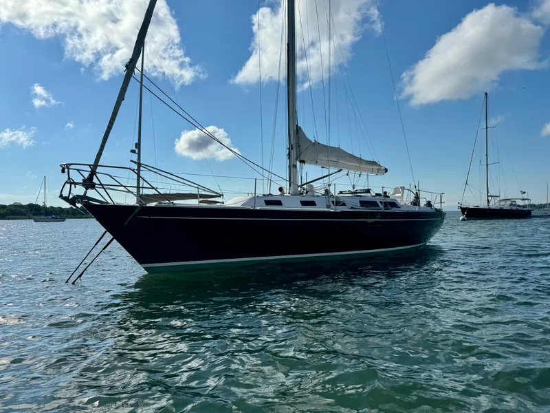 Slide: The Image of 1983 Islander 40 sailboat on calm water with blue sky and clouds. - 6