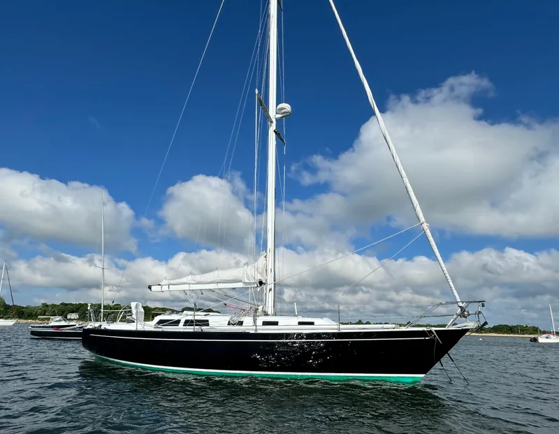 Slide: The Image of 1983 Islander 40 sailboat on calm water under a blue sky with clouds. - 7