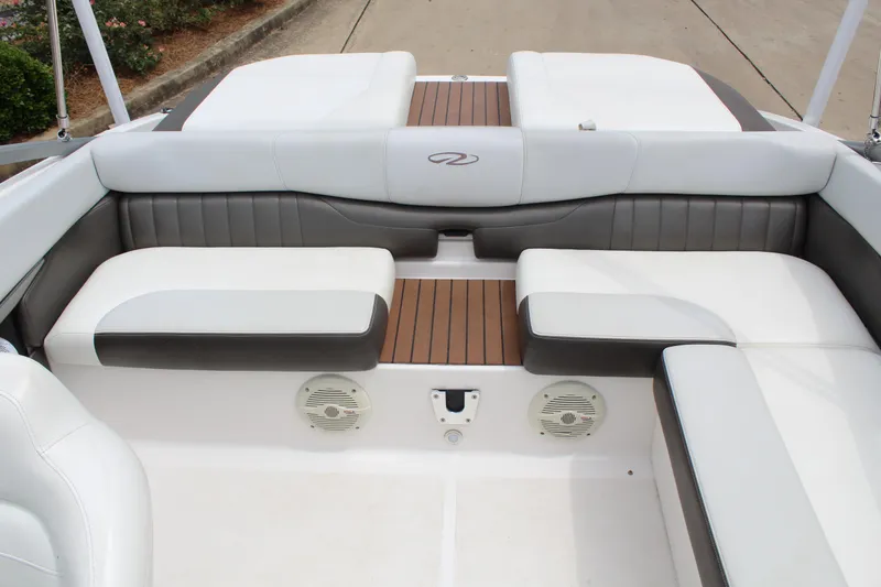 Slide: The Image of 2011 Regal 2100 boat interior with white and gray seating, wood accents, and speakers. - 14