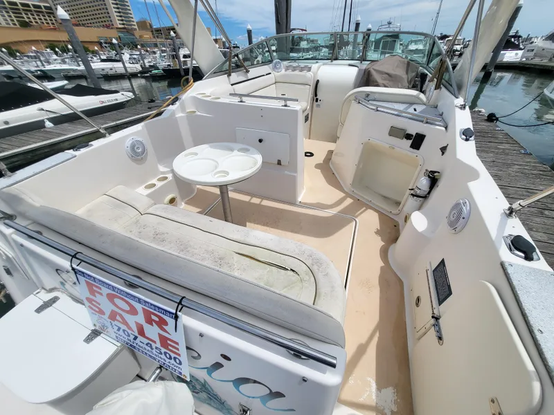 Slide: The Image of 2003 Rinker Fiesta Vee 270 boat interior with seating and "For Sale" sign at marina. - 13