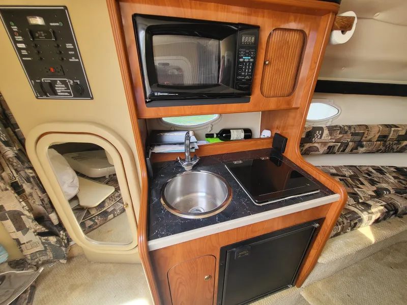 Slide: The Image of 2003 Rinker Fiesta Vee 270 interior kitchen with microwave, sink, and mini-fridge. - 2