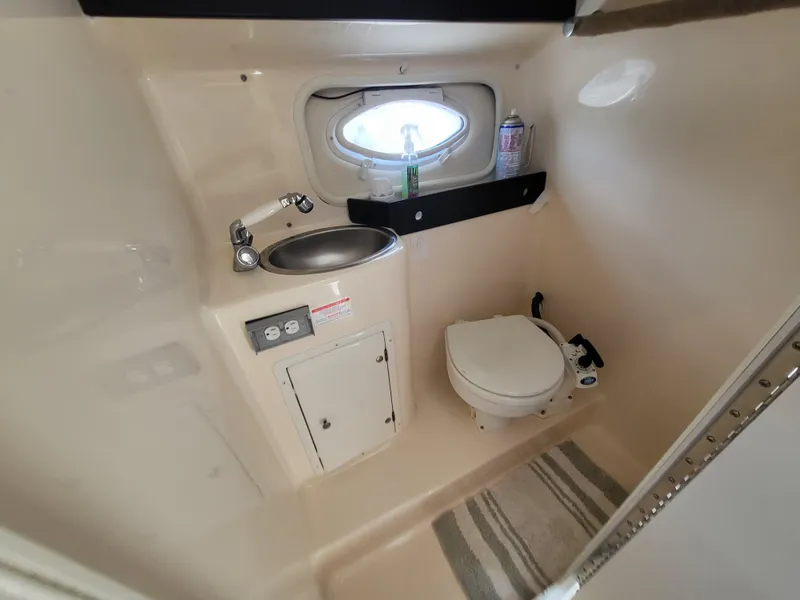 Slide: The Image of 2003 Rinker Fiesta Vee 270 boat bathroom with sink, toilet, and porthole window. - 25