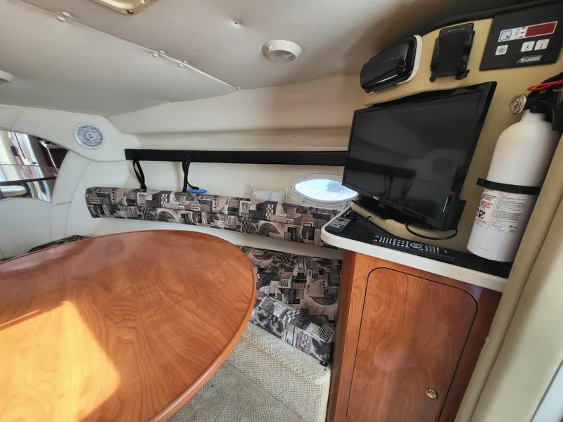 Slide: The Image of 2003 Rinker Fiesta Vee 270 cabin interior with table, TV, and fire extinguisher. - 6