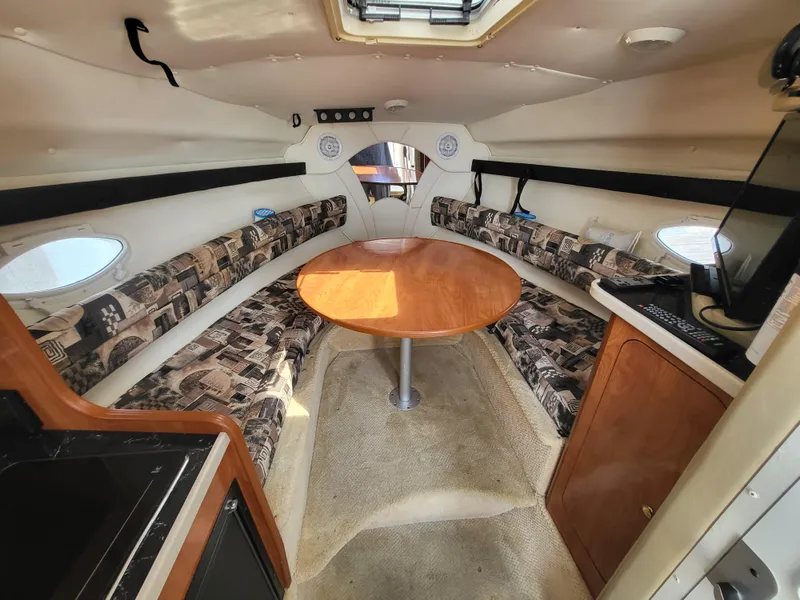 Slide: The Image of 2003 Rinker Fiesta Vee 270 cabin interior with circular seating and wooden table. - 8