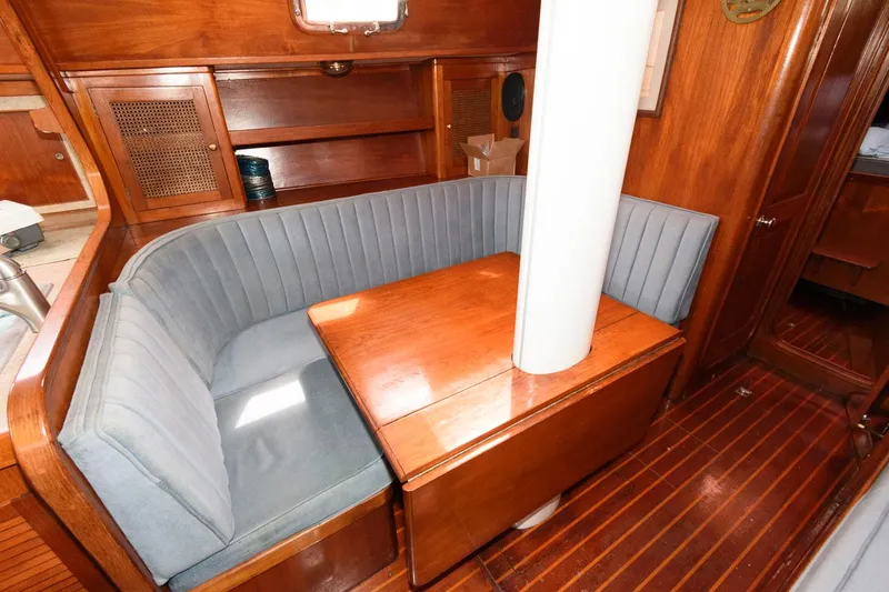 Slide: The Image of 1977 Gulfstar 50 Center Cockpit interior with wooden dining area and blue cushioned seating. - 21