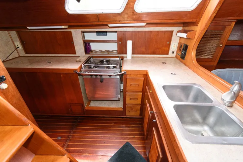 Slide: The Image of 1977 Gulfstar 50 Center Cockpit galley with stove, sink, and wooden cabinetry. - 24
