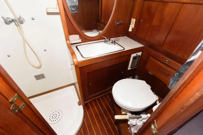 Slide: The Image of 1977 Gulfstar 50 Center Cockpit bathroom with wooden cabinetry, shower, sink, and toilet. - 26